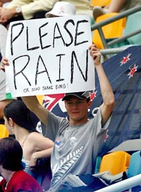 A New Zealand cricket fan holds a sign asking for rain to halt play on day four of the first Test against Australia in Brisbane