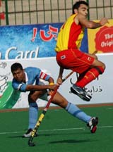 Spain's Eduard Arbos, right, avoides a hit of Indian captian Dilip Tirkey, left, in the 26th Men's Field Hockey Champions Trophy tournament in Lahore