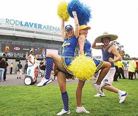 Tennis fans Linda Olsson and Mia Nordstrom of Sweden cheer for the cameras as Australian Luke Dean (R) tries to join in the front lawn of Rod Laver Arena, on the opening day of the Australian Open in Melbourne on Monday
