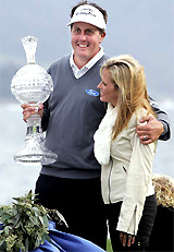 With his arm around his wife Amy, Phil Mickelson holds the victor's trophy after winning the AT&T Pebble Beach National Pro-Am in Pebble Beach, California