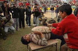 A man breaks a stone on the chest of Subhash Chander Sharma of Shahpur Kandi who lies on a nailed sheet during the 70th Kila Raipur Games on Friday