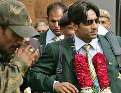 An Indian policeman escorts Pakistani cricket player Yousuf Youhana at Indira Gandhi International Airport
