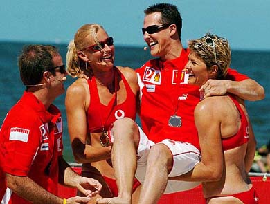 Ferrari's German world F1 champion Michael Schumacher is held aloft by his beach volleyball opponents, Australia's Olympic gold medallists Kerri Pottharst and Natalie Cook 