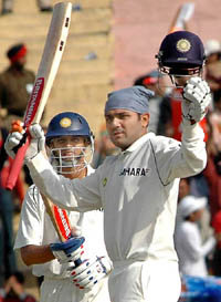Virender Sehwag acknowledges the crowd after scoring 150 runs as Rahul Dravid looks on during the third day�s play of the first Test in Mohali 