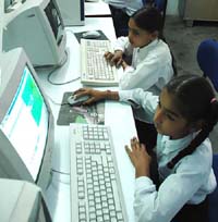 Children enjoy working on the computers as Dr Gill watches.