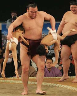 Sumo wrestler Takamisakari lifts two school boys during the one-day extra sumo tournament at the EXPO 2005 in Nagakute, central Japan