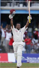 West Indies batsman Brian Lara raises his bat and helmet after scoring a century