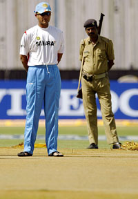 Sourav Ganguly inspects the pitch as a security guard looks on at the Motera stadium in Ahmedabad on Monday