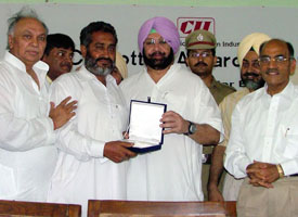 A farmer receives an award from Chief Minister Amarinder Singh for the highest cotton yield in Bathinda on Friday.
