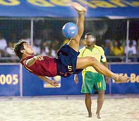 Ramiro Amarelle of Spain performs a scissors-kick as Romario Faria of Brazil looks on during their FIFA Beach Soccer World Cup match in Rio de Janeiro on Tuesday