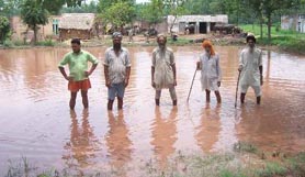 Villagers in front of their houses at Bal village where water entered houses due to breach in a seasonal rivulet