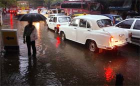 A man walks past stranded vehicles in a waterlogged street in Mumbai