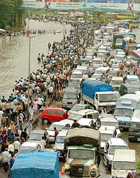 Commuters walk through floodwaters past stranded motor vehicles after heavy torrential rains paralysed life in Mumbai on Wednesday.