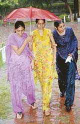 Three girls make the most of one umbrella during heavy rain at Patiala on Monday.