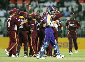 Sri Lankan batsman Kumar Sangakkara walks back to the pavilion as West Indies players celebrate his dismissal during the tri-series match at the R. Premadasa Stadium in Colombo on Saturday