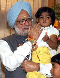 Prime Minister Manmohan Singh carries a young girl after she tied a rakhi on his wrist on the occasion of Raksha Bandhan in New Delhi