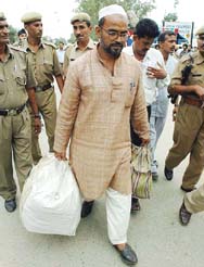 Pakistani prisoner Mohammad Babbar Sayyad is escorted by security men at the Wagah joint checkpost, in Amritsar on Monday. 