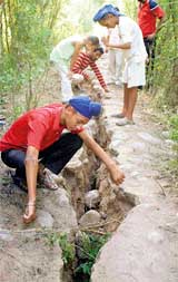 Children look at a huge crack caused by an earthquake in Simbal camp, about 25 km southwest of Jammu, on Sunday