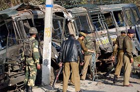A jawan stands guard near a damaged vehicle after militants set off a car bomb at Lawaypora on the Srinagar-Baramula highway