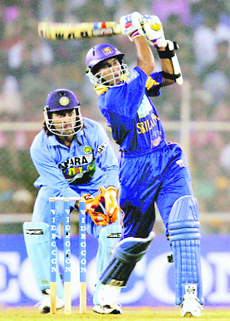 Tillakratne Dilshan of Sri Lanka plays a shot as Mahendra Dhoni looks on during the fifth one-day match in Ahmedabad on Sunday.