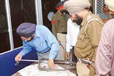 A fingerprint expert examines the gun of the bank guard, which was snatched by the robbers in Jalandhar on Thursday.