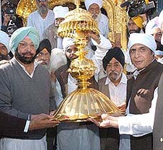 Punjab Chief Minister Amarinder Singh presents the Golden Palki to Mr Pervaiz Elahi, Chief Minister of Pakistan Punjab, at Gurdwara Janam Asthan, Nankana Sahib, on Wednesday.