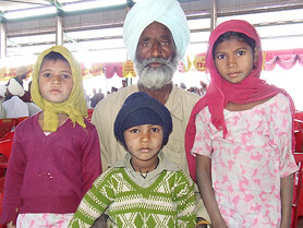 Hari Singh (70) with his grandchildren at a Lok Suvidha camp in Goniana Mandi, near Bathinda, on Wednesday.
