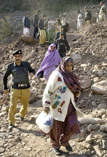A Pakistani policeman assists elderly Kashmiri women as they cross the Line of Control near the damaged Kaman Bridge at Kaman Post, 53 km south of Muzaffarabad, on Thursday.