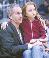 Former tennis star John McEnroe sits with his daughter Ava as they watch the NBA game between the Houston Rockets and the Los Angeles Lakers in Los Angeles