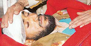 An injured bus accident victim is comforted by his relative at a hospital in Rajouri on Friday.