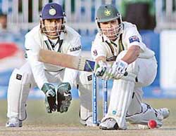 Kamran Akmal plays a stroke as wicketkeeper Mahendra Singh Dhoni looks on during the fourth day of the second Test in Faisalabad on Tuesday. 