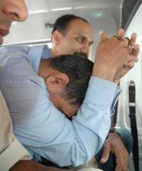 Vinod Kumar Jha, a former Commandant of the Navy, hides his face as he is produced at the Tees hazari Court in New Delhi in the war room leak case on Saturday