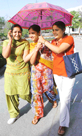 College girls brave the sun under an umbrella in Patiala on Thursday.