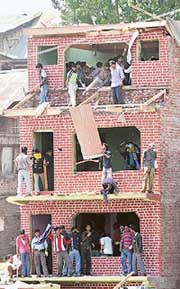 Protesters destroy the house belonging to Sabina, a Kashmiri woman who has been charged with being involved in a sex scandal, in Srinagar on Friday.