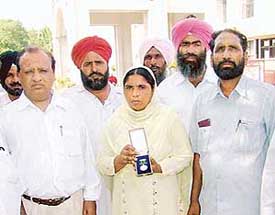 Manjit Kaur shows Kirti Chakra awarded to her husband Jora Singh posthumously in front of Moga mini-secretariat on Tuesday.