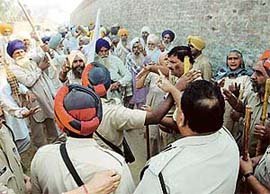 Police personnel prevent farmers from sowing wheat on the land acquired by the government at Dhaula village in Barnala on Wednesday.