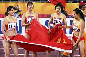 Members of China�s 4x100m relay team (from left) Han Ling, Chen Jue, Wang Jing and Qin Wangping celebrate with the national flag after winning the gold medal