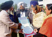 The secretary of the Lambra-Kangri Multipurpose Cooperative Service Society, Mr Chander Dev Singh (left), and other members pose with the trophy and certificate of excellence that the society got as part of the national award for its activities.