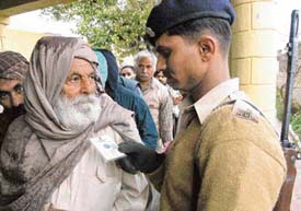 A security man examines the I-card of a voter at a polling centre in Kharar on Tuesday