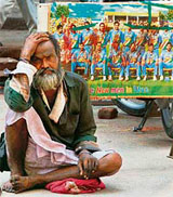 A cricket fan sits dejected beside a defaced poster of Team India in Guwahati.
