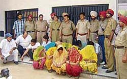 Policemen with the persons arrested for their involvement in a flesh trade racket busted in Mukerian on Monday