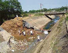 The work of plugging a breach, that developed in the Kandi canal (stage-I) on Sunday, in progress at Datarpur village, near Talwara, on Monday.