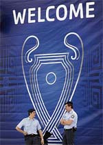 Two policemen stand in front of a Champions League poster in Athens on Tuesday. More than 50,000 Liverpool and AC Milan fans are expected to arrive in Athens for the final of the Champions League on Wednesday