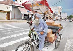 Necessity is the mother of invention: An aged rickshaw-puller protects himself from the scorching heat by �inventing� a colourful umbrella for himself in Bathinda on Friday.