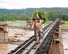 A farmer and two school students take a short cut over a narrow-gauge railway bridge following the collapse of Chakki bridge, near Pathankot, on Sunday.