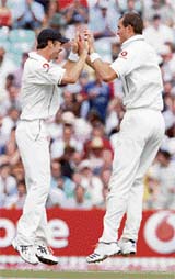 England�s Chris Tremlett (right) and James Anderson celebrate the dismissal of Dinesh Karthik on the fourth day of the third Test at the Oval on Sunday. 
