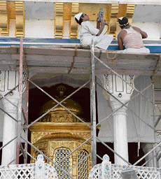 Workers fix gold plates during kar sewa at Akal Takht in Amritsar on Sunday.