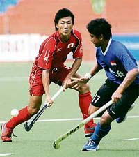Japanese field hockey player Sakamotohiroki (L) is watched by Singaporean player Mohammed Sabri Bin after playing a shot during a first round match for the seventh Asia Cup hockey tournament in Chennai