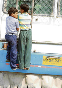 Schoolchildren cling dangerously to an overcrowded bus in Hisar.
