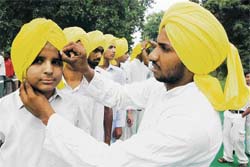 A youth ties a basanti-coloured turban in Shaheed Bhagat Singh style to participate in a chetna march to commemorate the centenary birth anniversary of the martyr in Amritsar on Saturday. 